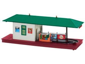 Miniature train station model with green roof, red base, and small platform details