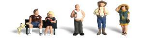 Four small figurines posing on a white background, including seated and standing characters with hats and baggy clothes