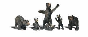 Five small animal figurines standing and sitting in a row on a white background