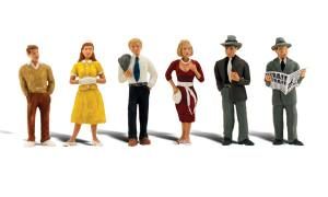 Six small figurines standing in a row, dressed in colorful vintage-style clothes.