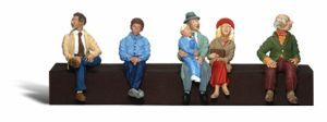 Five figurines sitting on a bench, each in different colorful outfits.