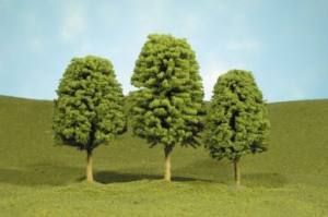 Three leafy green trees on a grassy hill under a blue sky