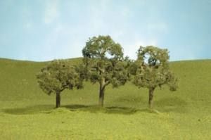 Three small trees on a grassy hill under a blue sky.