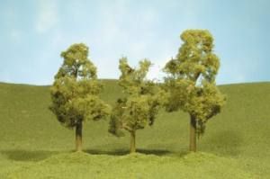 Three small trees on a grassy hill under a blue sky