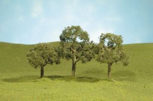Three small trees on a grassy hillside under a blue sky