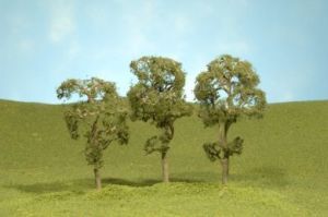 Three small trees on a grassy hill under a blue sky