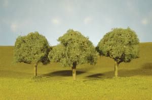 Three small trees in a grassy field under a pale sky
