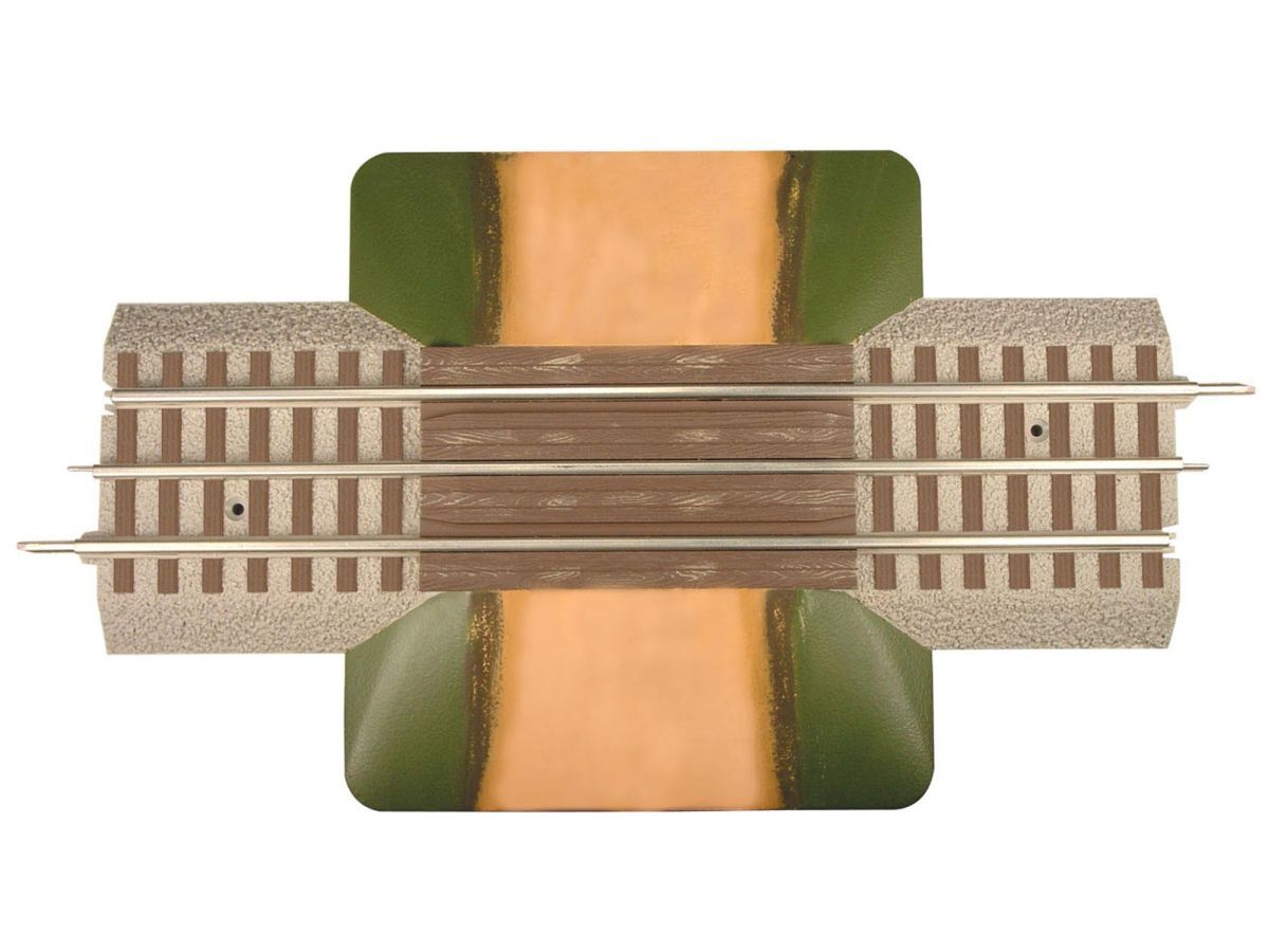 Top-down view of a model railroad track crossing a green-and-brown terrain piece