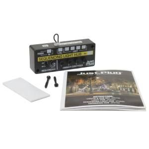 Black electronic device with buttons, screws, adapter, and instruction booklet on white background