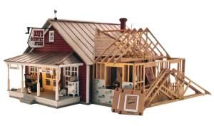 Half-built red house model with exposed wooden roof framing and porch detail