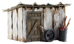 Rustic weathered wooden shed with corrugated metal, a wheel leaning outside, and tools in a barrel.