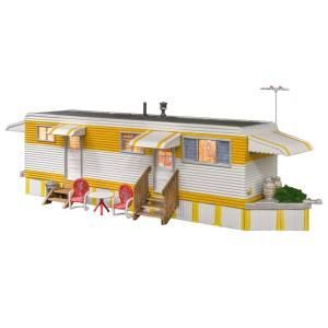 Toy model of a white trailer with yellow trim, porch, and tiny figures outside