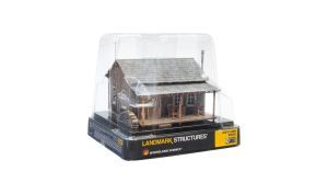 Toy log cabin model in a clear display box, with a black and yellow base.