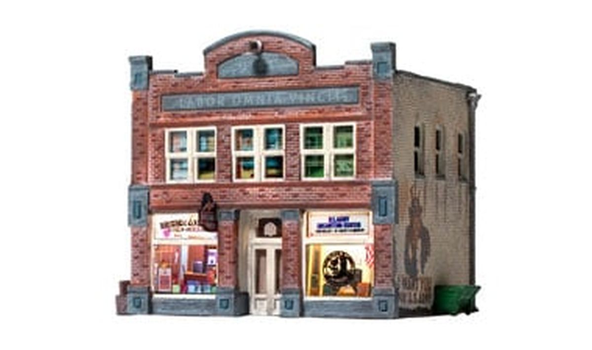 Miniature red-brick storefront with painted windows, arched roofline, and shop displays on the ground floor