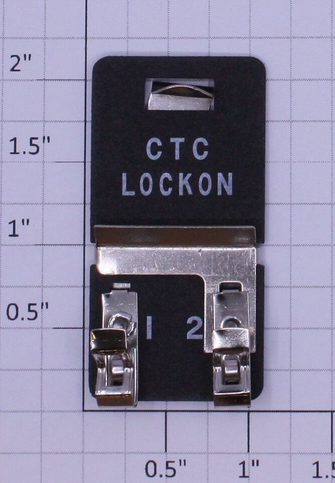 Black CTC lock-on clip with metal clamp, shown against a measurement grid.
