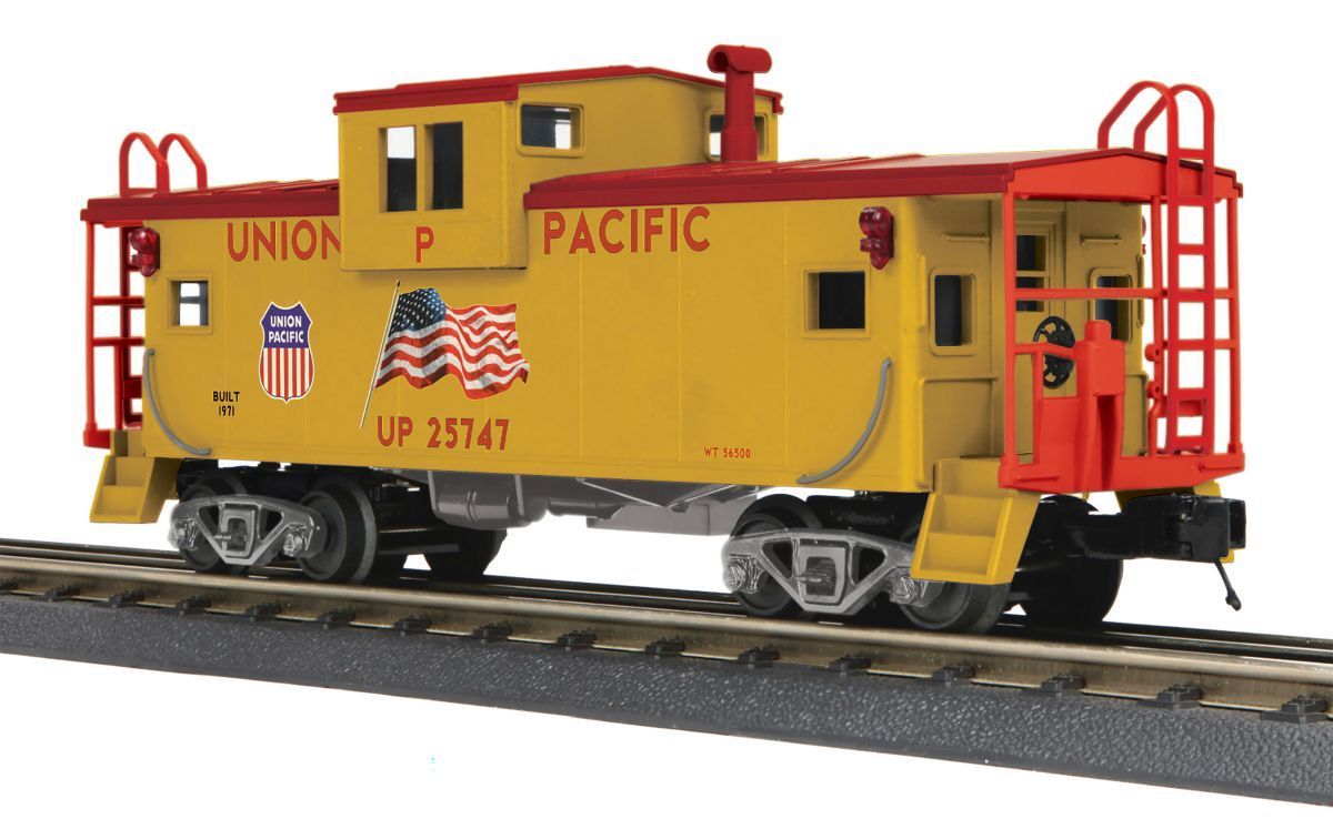 Yellow Union Pacific caboose on train tracks, with red railings and black wheels.