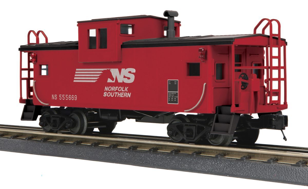 Red caboose railcar on tracks, painted red with white lettering and black wheels.