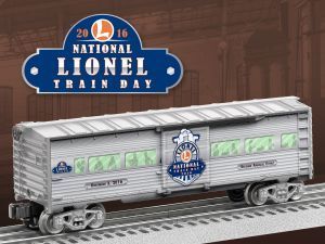 Silver Lionel train car with green windows on tracks, beside a 2016 National Lionel Train Day logo