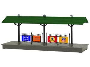 Model of a covered train platform with green roof, black supports, and colorful signs behind the fence