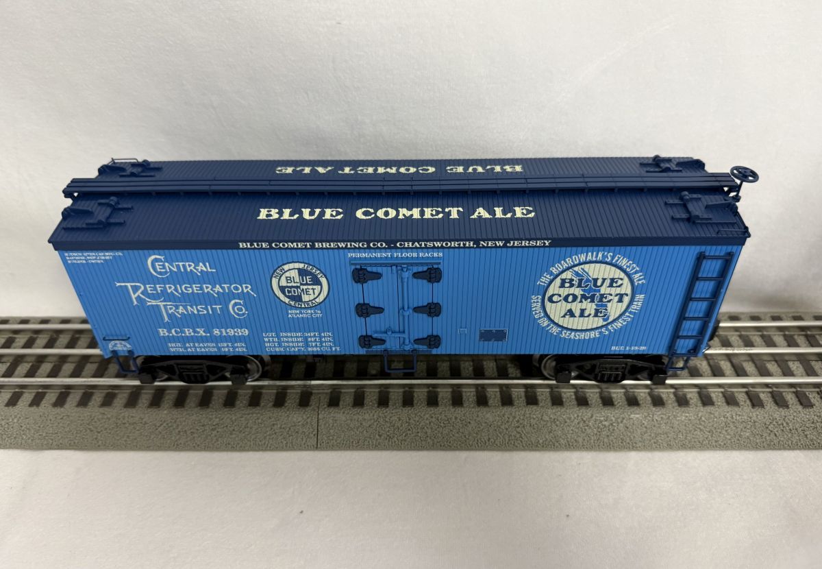 Blue CSX freight boxcar on model train tracks, with white lettering and logos on a blue body