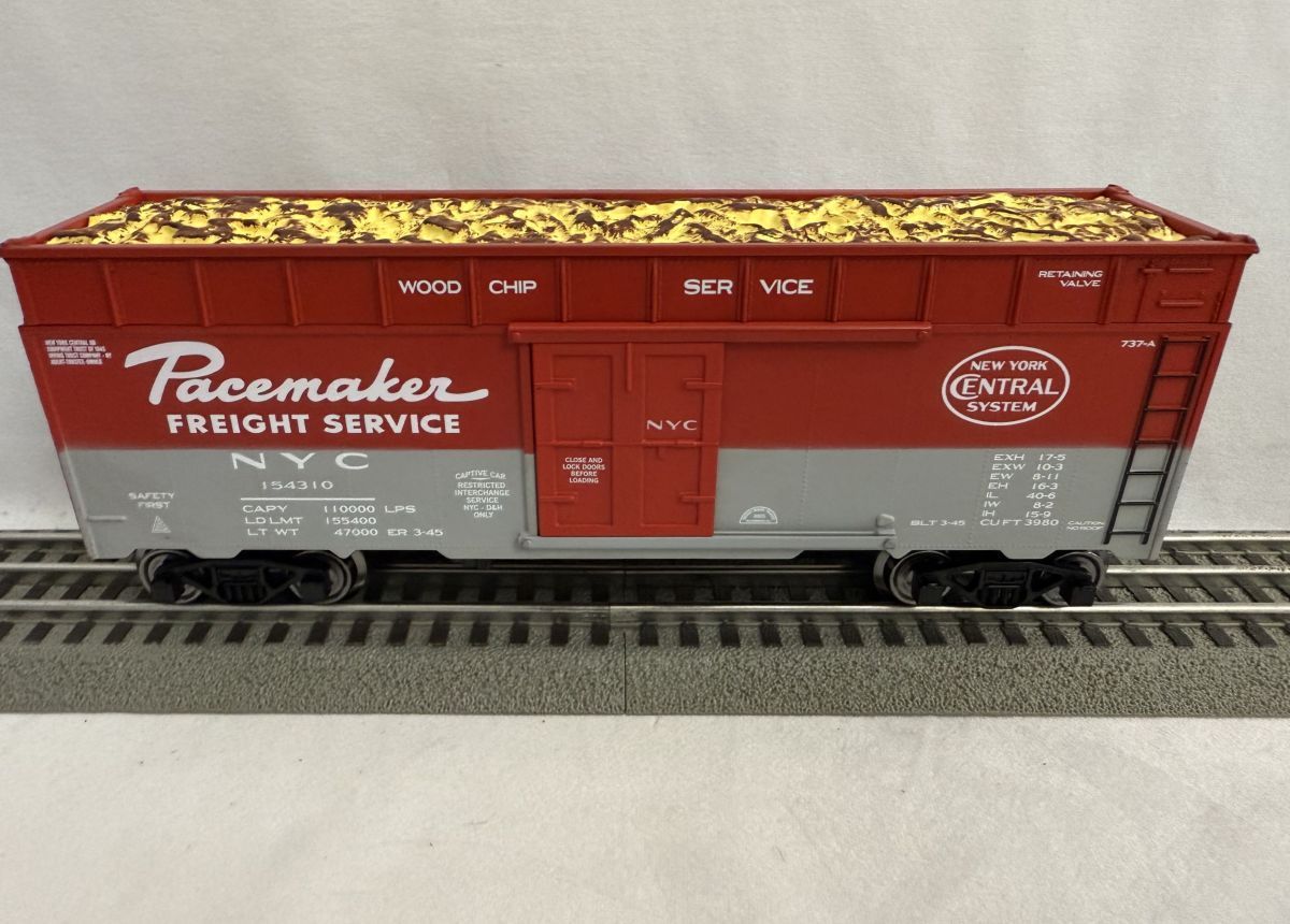 Red and gray Pacemaker Freight Service boxcar model on train tracks