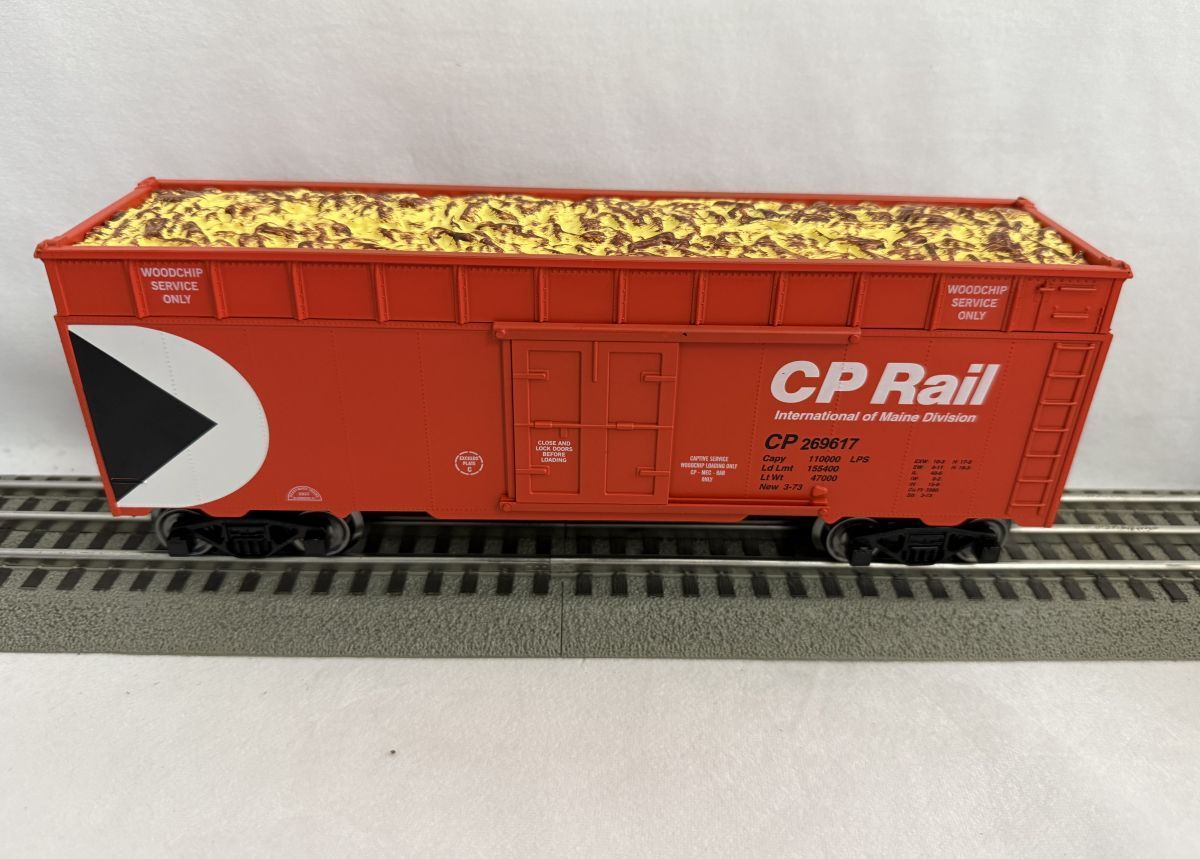 Red CP Rail hopper car filled with yellow gravel on railroad track