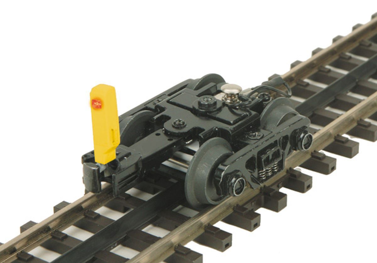 Black toy rail cart on train tracks with a yellow rear marker.