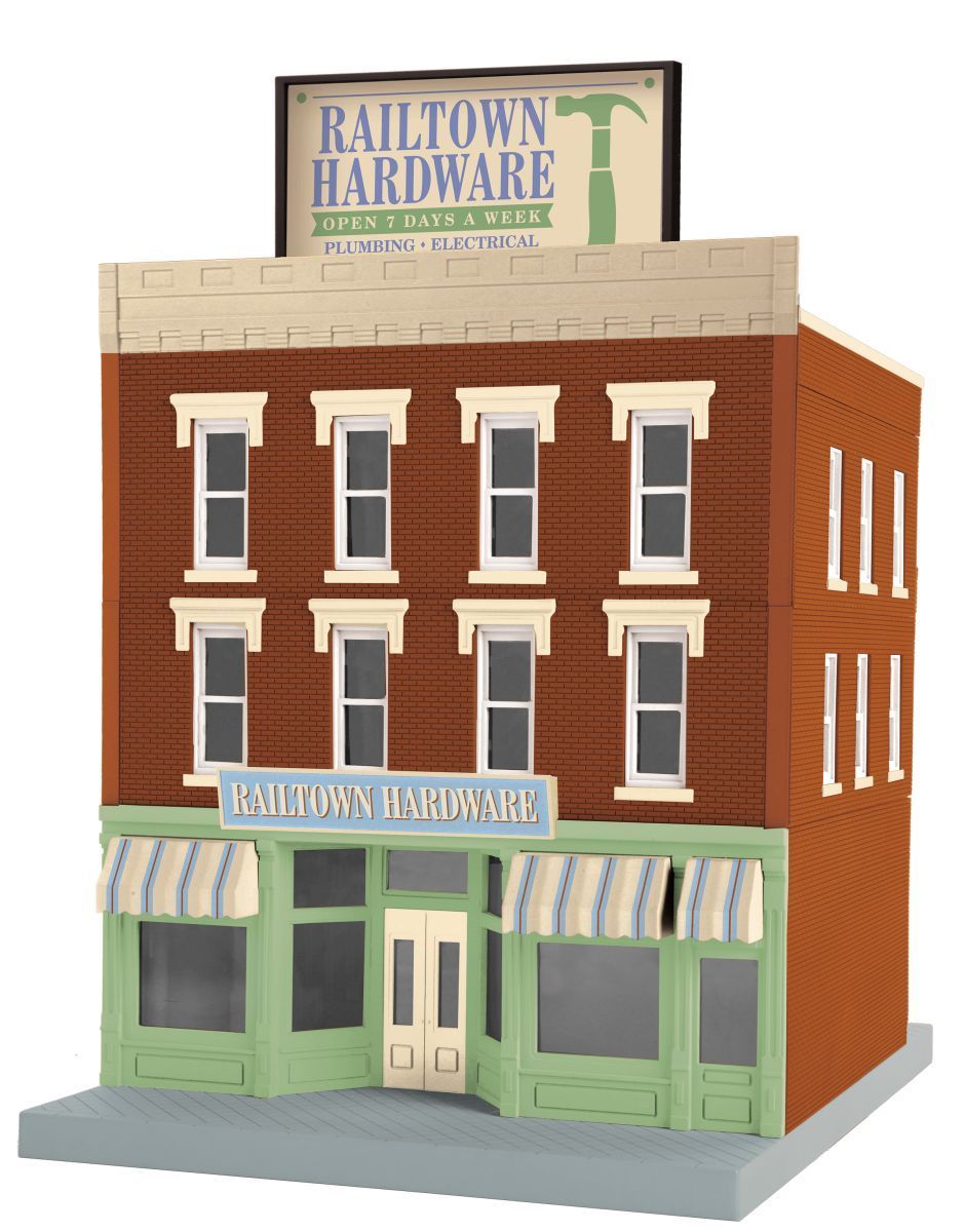Miniature red-brick hardware store with green storefront and striped awnings, topped by a large sign.