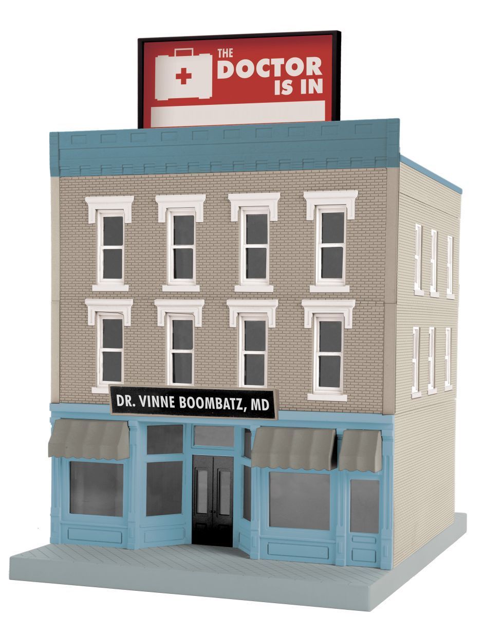 Model of a three-story brick doctor’s office with a red “Doctor Is In” sign and blue storefront windows.