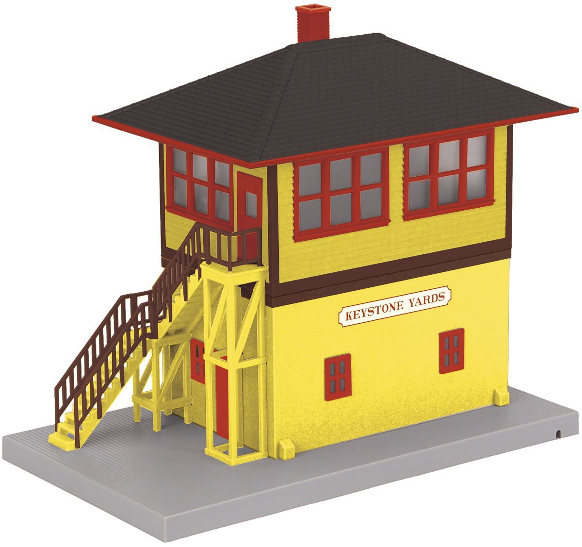 Yellow fire lookout tower model with red windows, brown roof, and exterior stairs on a gray base
