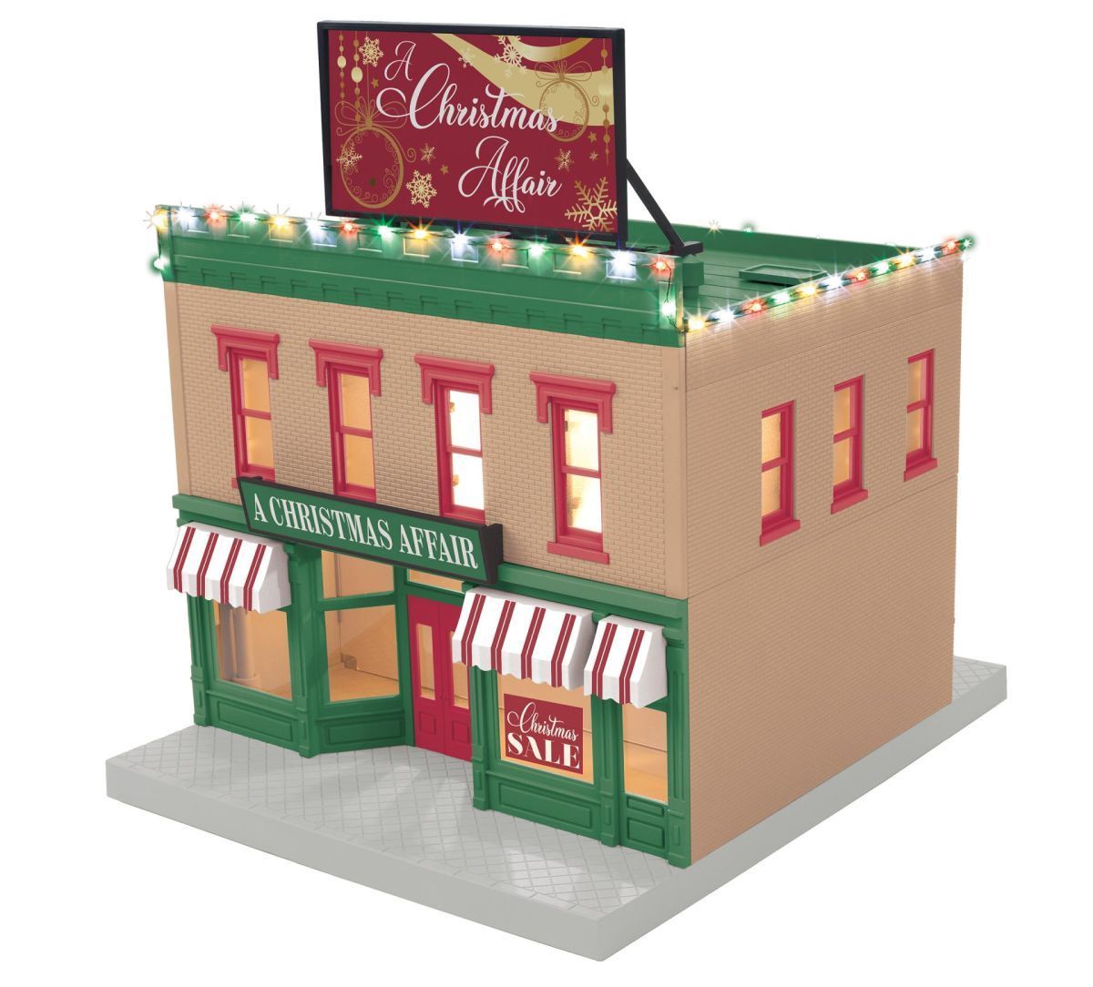 Miniature Christmas storefront with red-and-green trim, lit windows, and a rooftop holiday sign.