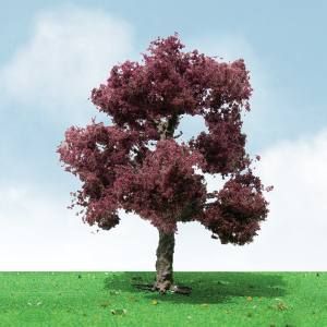 Small tree with burgundy leaves on green grass under a bright blue sky