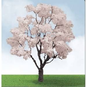 Single flowering tree with pale pink blossoms on green grass under a blue sky