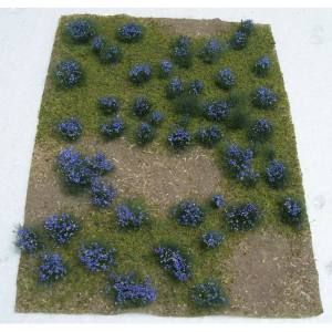 Square patch of grass with scattered blue-purple flowers forming a loose pattern on a white background