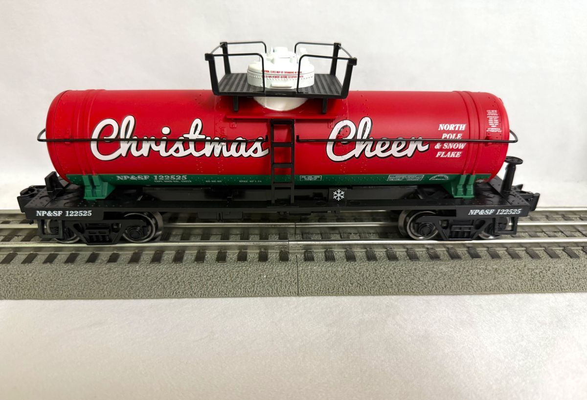 Red Christmas Cheer tanker train car on tracks, with a catwalk on top and black base