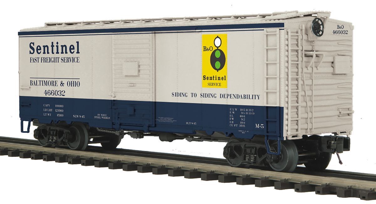 White Sentinel boxcar with blue lower half and yellow hazard sign on tracks