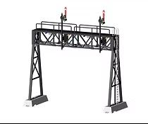 Model of a railway signal gantry with two red signals, black metal truss, and support legs on concrete bases
