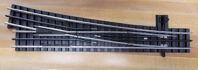 Black window blind track with white cords on a wooden surface
