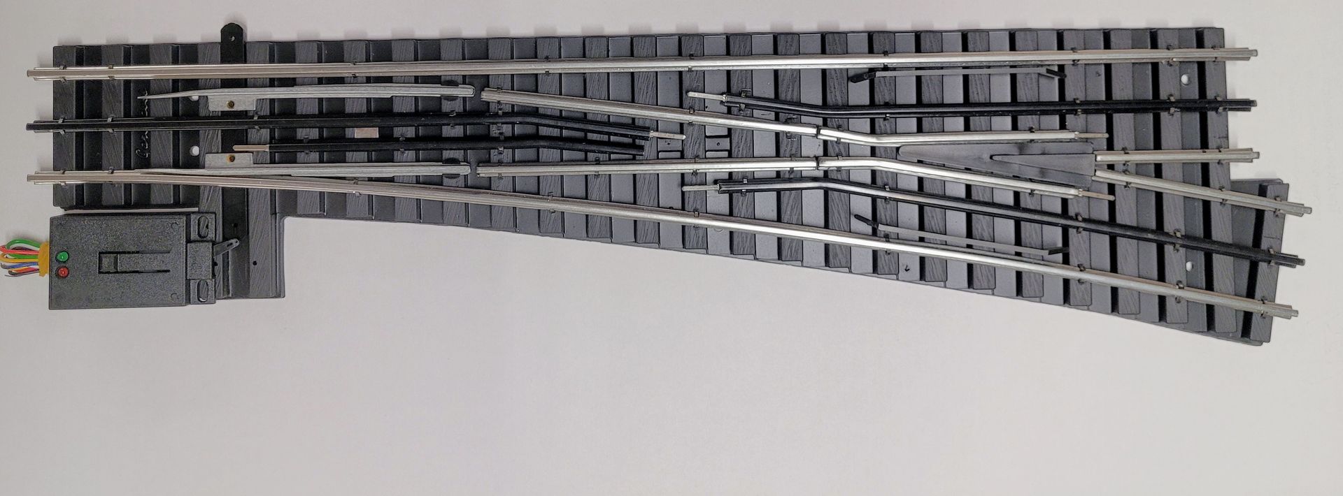 Gray railroad track switch turnout with multiple curved metal rails on a white background