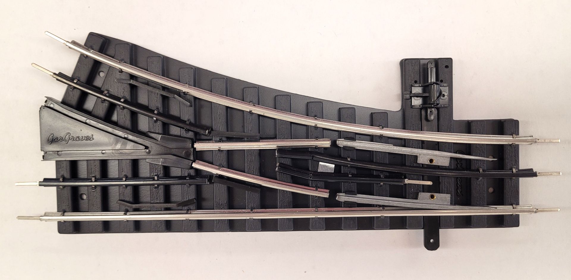 A model railroad switch track assembly with multiple curved and straight black rails on a white background