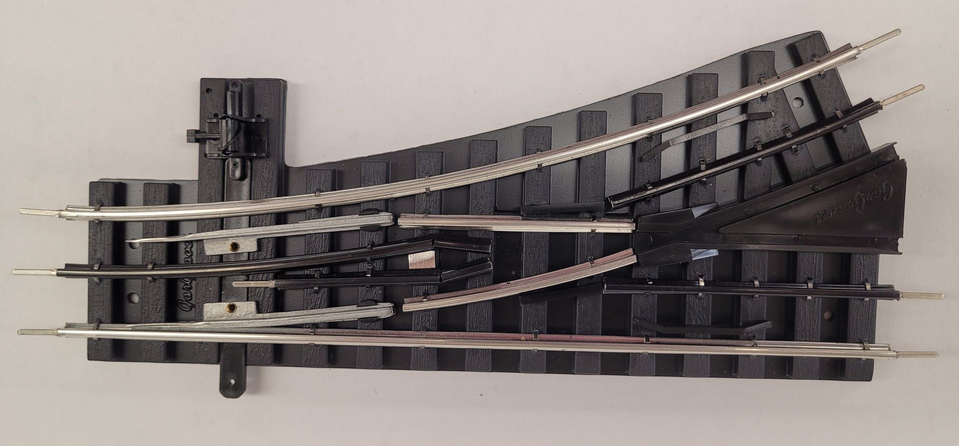 Close-up of a black model railroad switch track with multiple parallel rails and curved turnouts