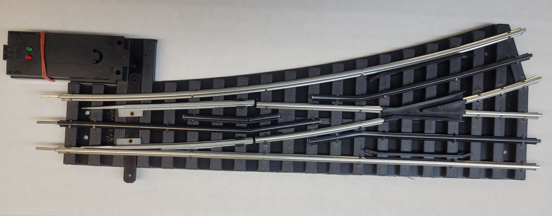 Model railroad track switch with multiple curved rails on a white background