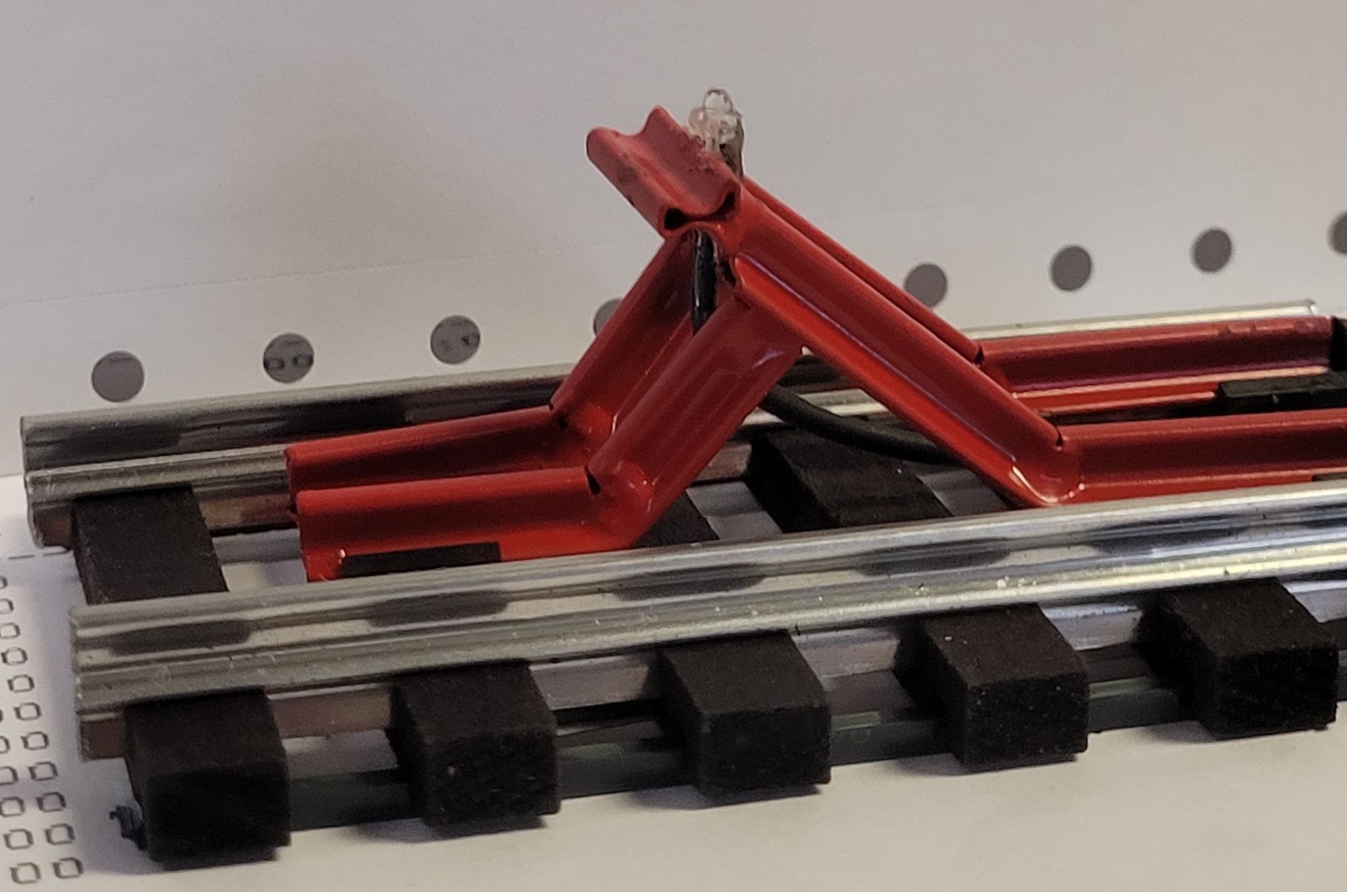 Red toy car on a gray train track display with black blocks underneath