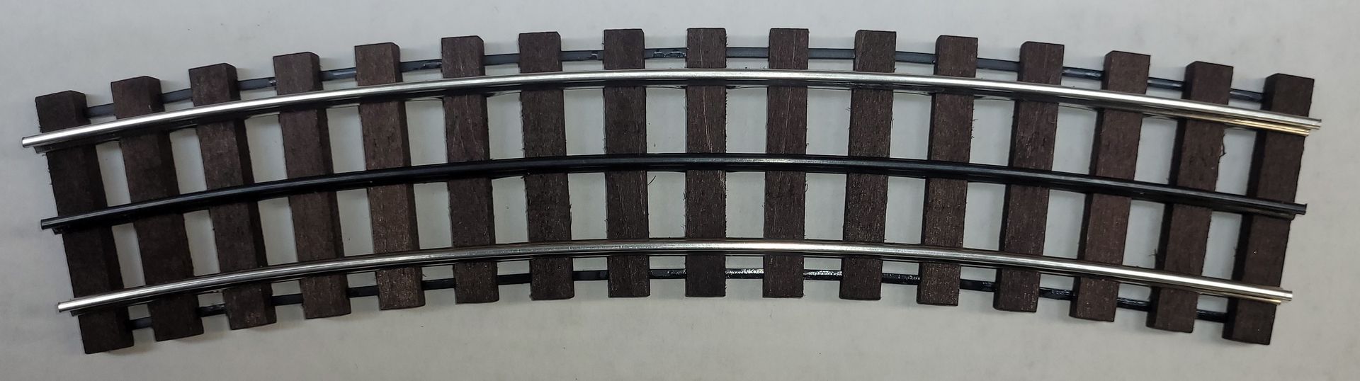 Curved model train track section with black rails and brown ties on a white background