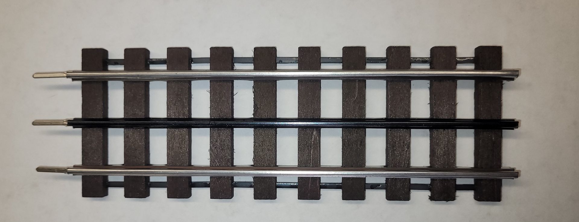 A short section of model railroad track with two parallel rails on a white background