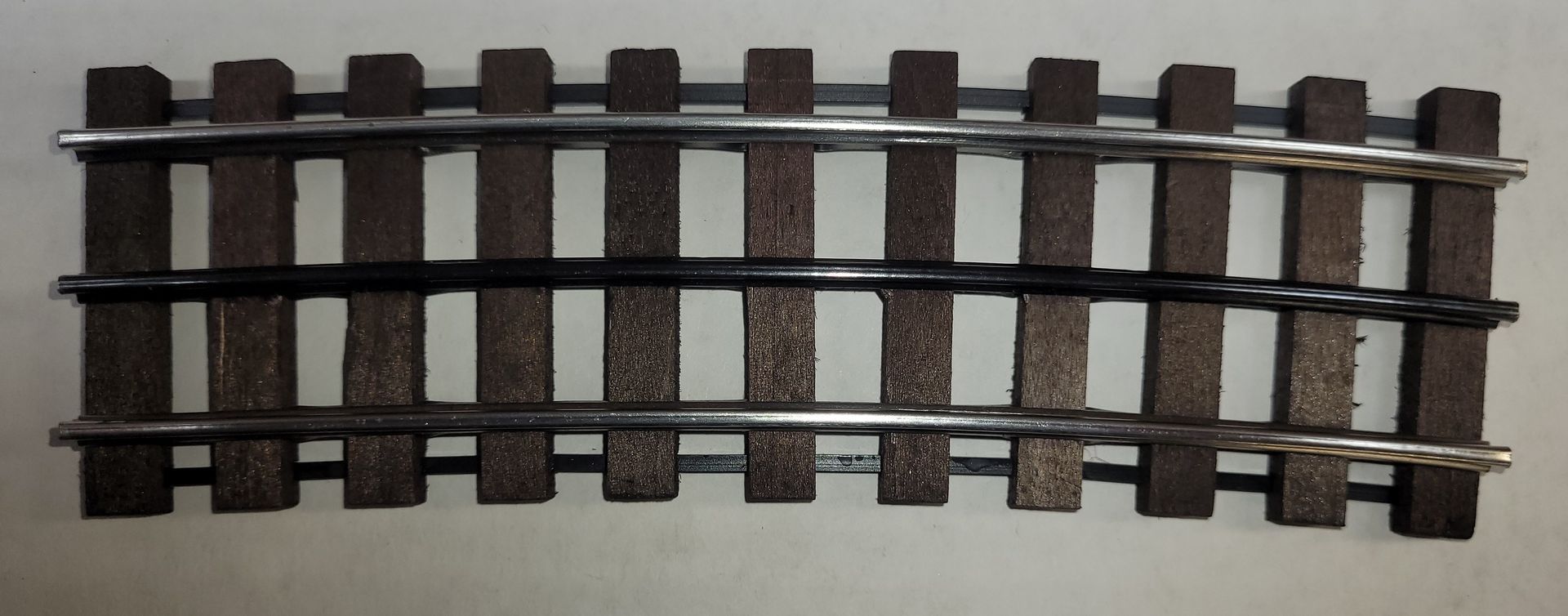 Close-up of a curved model train track section on a light background