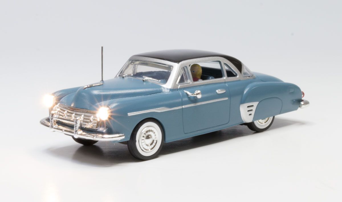 Blue vintage car model with white roof and headlights on, shown on a plain white background