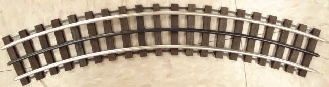 Curved model railroad track on a beige surface
