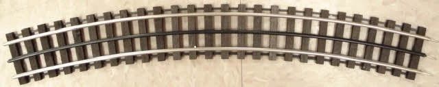 Curved model railroad track section with black rails and brown ties on a light background