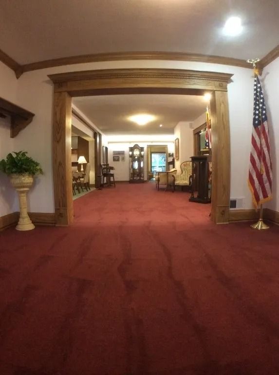 Grand hotel lobby with red carpet, wood trim, and an American flag by the entrance